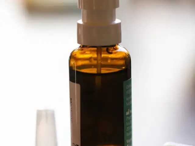 A nasal spray bottle beside medication capsules.